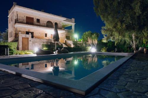 a swimming pool in front of a building at night at Seaside "Stone & Light Villa" close to Aegina City in Khlóï