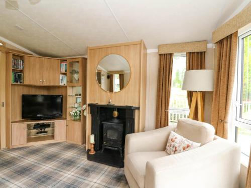 a living room with a couch and a fireplace at The Four Oaks Chalet in Fassfern