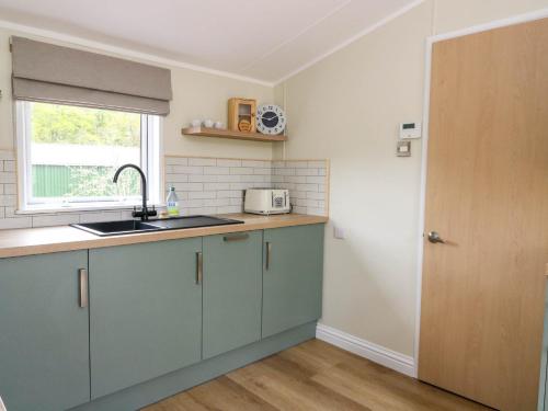 a kitchen with blue cabinets and a sink and a window at The Four Oaks Chalet in Fassfern