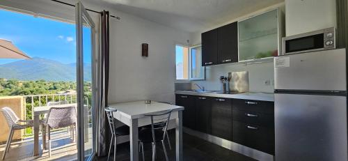 Il comprend un balcon et une cuisine équipée d'un réfrigérateur et d'une table. dans l'établissement Studio Dolce & Vita D1, vue mer et Piscine, à Propriano