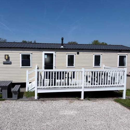 a white house with a porch and a white fence at McCanns Caravan Marton Mere in Blackpool