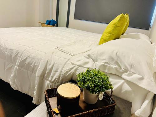 a bed with a white blanket and a table with a plant at Depa Equipado Zona de Estadios & Restaurantes in Veracruz