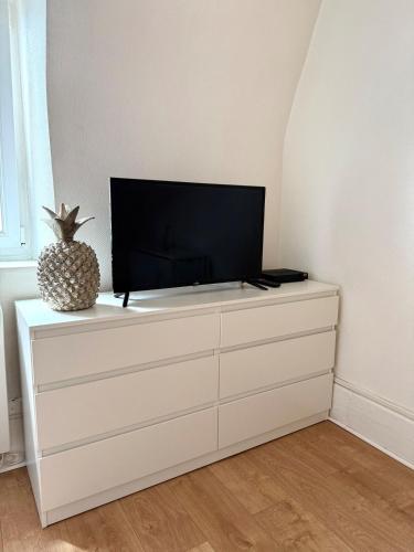 Elle comprend une télévision à écran plat installée au-dessus d'une commode blanche. dans l'établissement Studio tout confort cité de la gastronomie (4), à Dijon