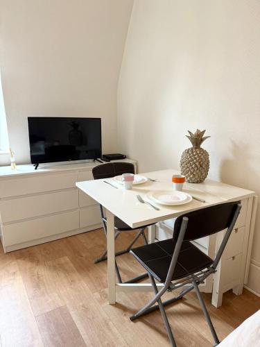 une table blanche avec deux chaises et un ananas dessus dans l'établissement Studio tout confort cité de la gastronomie (4), à Dijon