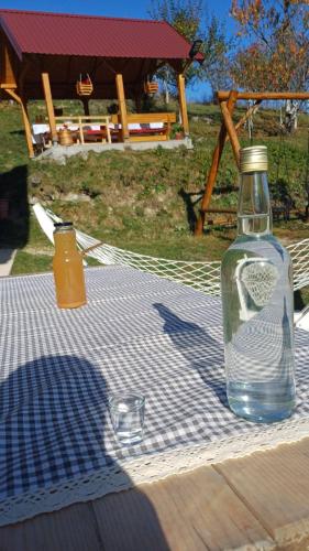 a glass bottle sitting on a picnic table with a drink at Seosko domaćinstvo Desin Do in Berane
