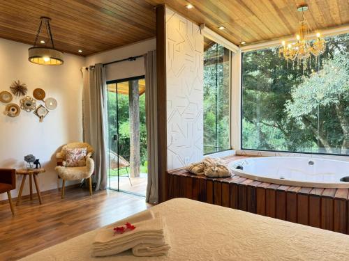 a large bathroom with a tub and a window at Chalé Refúgio Bem-Te-Vi in São Bento do Sapucaí
