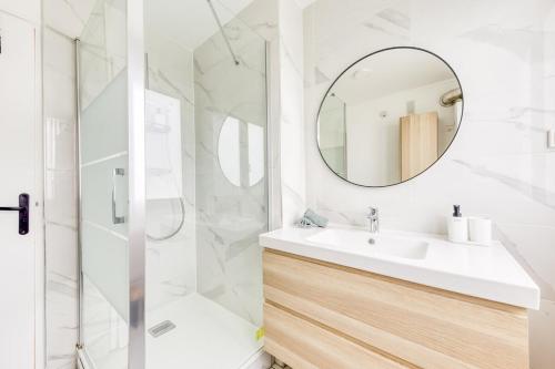 une salle de bain blanche avec un lavabo et un miroir dans l'établissement Appartement 8 personnes à Saint-Denis, à Saint-Denis