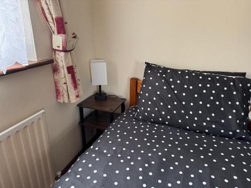 a bed with a polka dot pillow and a lamp at Rusty Cottage in Blacklion