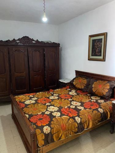 a bedroom with a bed with a floral bedspread at Maison Chkili in Bin Rhilouf
