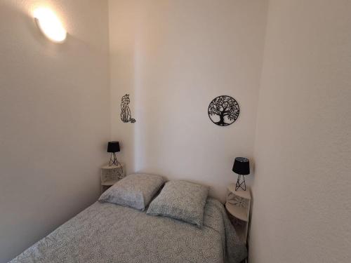 a small bedroom with a bed and two lamps at Maison fleurs des sables in Valras-Plage