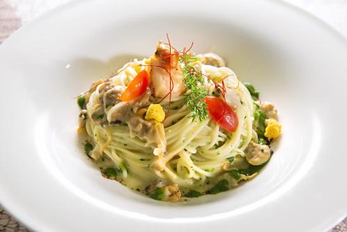 a white bowl of pasta with vegetables and sauce at Bibione Palace Hotel in Bibione