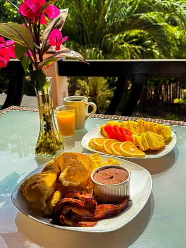 two plates of food on a table with drinks and flowers at Caribbean Shores Belize in Hopkins