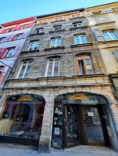 un grand bâtiment en briques avec une façade de magasin dans l'établissement Appartement vieille ville Le Puy, au Puy-en-Velay