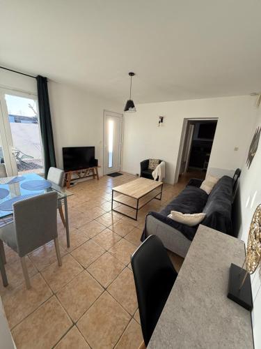 una sala de estar con un sofá y una mesa en Maison T3 avec jardin, en Narbona