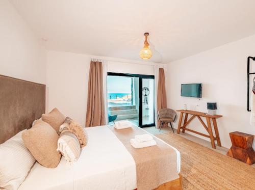 a bedroom with a large white bed and a desk at Shark Luxury Villa in Agios Ioannis Mykonos