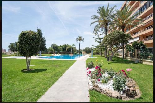 Un camino a través de un parque con flores y una piscina. en Estudio vistas campo golf y piscina, en Torremolinos