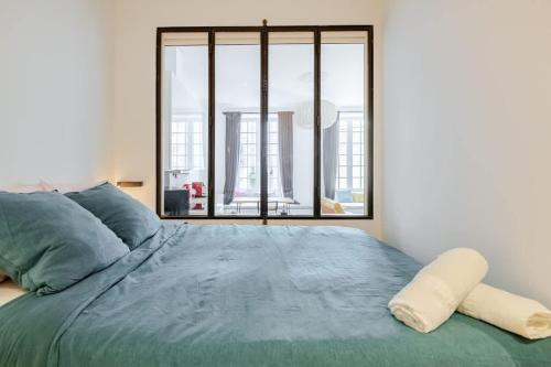 une chambre avec un grand lit avec une grande fenêtre dans l'établissement Chemin du muguet T2 hyper centre, à Bordeaux