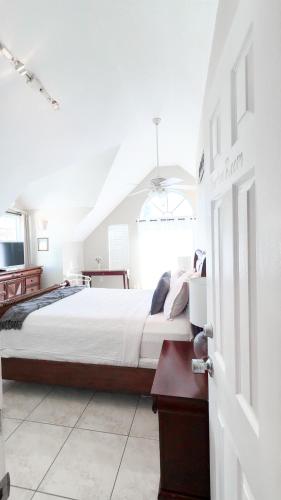 a white bedroom with a bed and a window at Shangri-La Boutique Bed & Breakfast in West Bay