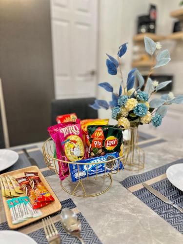a table with a basket of snacks and a vase of flowers at Rattanasup House in Hat Yai