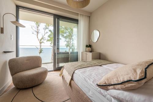 a bedroom with a bed and a chair and a window at Harbour Pearl Rewal BEST 3-RD FLOOR VIEW! With bikes and SPA acces in Rewal