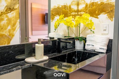 a bathroom with a black counter top with yellow flowers at Flats Confortáveis em Manaíra Mindset - Qavi in Tambaú