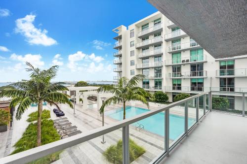 an apartment balcony with a pool and palm trees at Nomada Destination Residences - Quadro in Miami