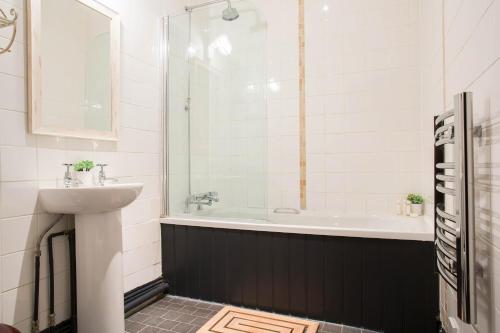 a bathroom with a sink and a bath tub at The Curious Pig in the Parlour in Burstow