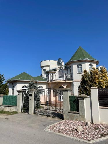 a large white house with a gate and fence at Diplomat Haven in Sremska Kamenica
