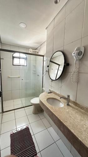 a bathroom with a sink and a shower and a mirror at Magnus Pousada in Paraty