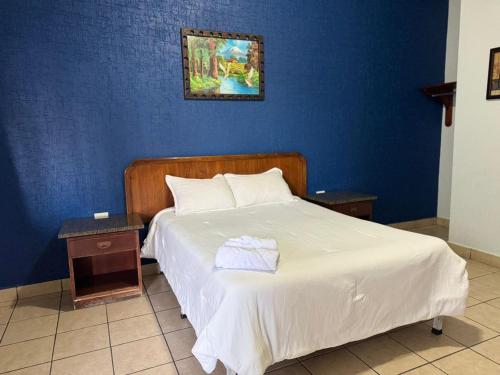 a bedroom with a white bed with a blue wall at Rio inn in Delicias