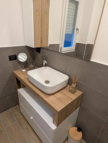 a bathroom with a white sink on a wooden counter at Apartment Eleven - 4 guests in Novara