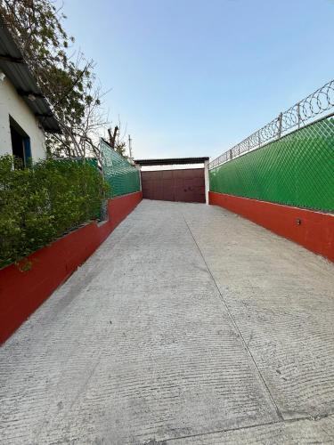 a tennis court with a fence next to a building at Lomeli’s Home, 5 minutos del Tunco in La Libertad