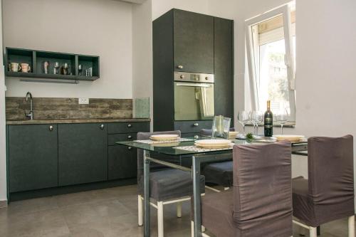 a kitchen with green cabinets and a table with chairs at Apartments More in Kožino