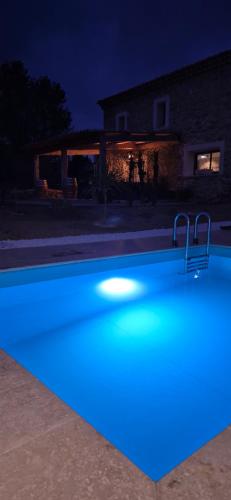 une piscine éclairée en bleu dans une cour la nuit dans l'établissement Tournissan L'Auberge du Chateau avec ça piscine, à Tournissan