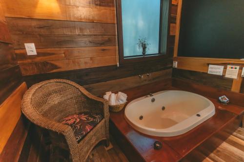 a bathroom with a tub and a chair in it at Pousada Vila Tamarindo Eco Lodge in Florianópolis