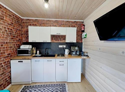 a kitchen with white cabinets and a brick wall at Domek Sielski Zakątek Pieniny in Szczawnica