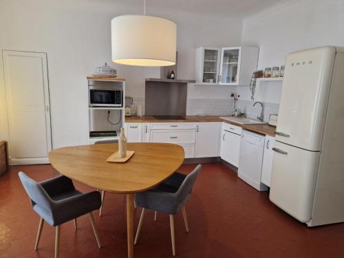 une cuisine avec une table et des chaises et un réfrigérateur blanc dans l'établissement Au Passage Niçois, à Nice