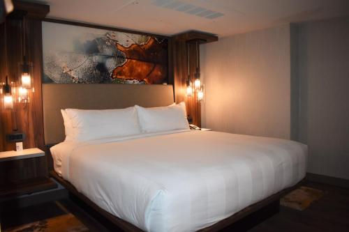 a bedroom with a large white bed with a painting on the wall at Chicago Marriott Oak Brook in Oak Brook
