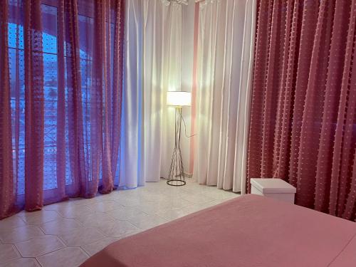 a bedroom with pink and white curtains and a lamp at Bella Vista in Balíon