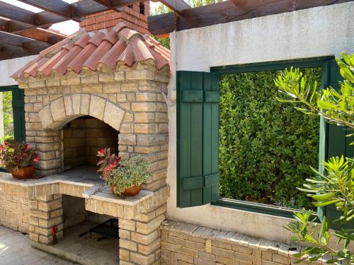 a brick fireplace with a green window and potted plants at Barbat 249 in Barbat na Rabu