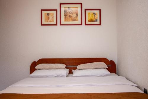 a bed in a room with three pictures on the wall at Guest House Jedro in Petrovac na Moru