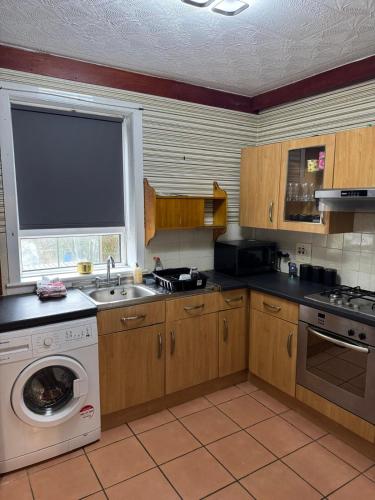 a kitchen with a washing machine and a sink at Chic & Cozy 2BR Semi-Detached in Kilmarnock