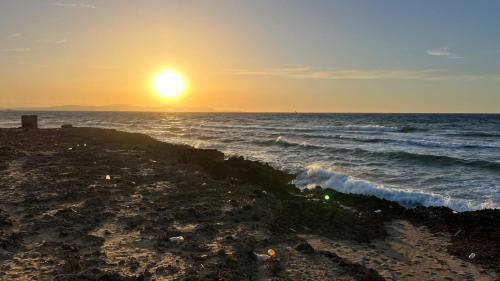 a sunset on a beach with the ocean at Résidence Le Marin in Banī ‘Aţāʼ