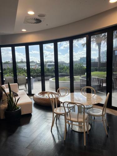 a living room with a table and chairs and a large window at Entire flat w infinity pool and 5m walk to Fort Valley station in Brisbane