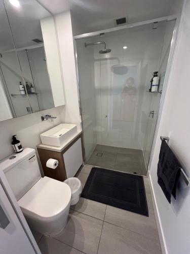 a white bathroom with a shower and a toilet at Entire flat w infinity pool and 5m walk to Fort Valley station in Brisbane