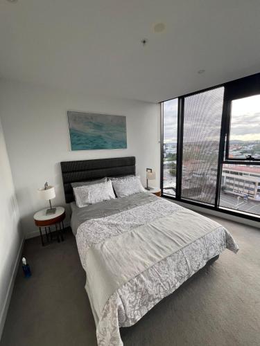 a bedroom with a large bed and large windows at Entire flat w infinity pool and 5m walk to Fort Valley station in Brisbane