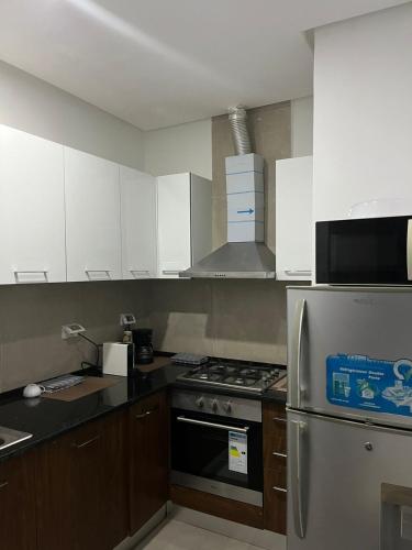 a kitchen with white cabinets and a stainless steel refrigerator at Le Chill Out in La Marsa