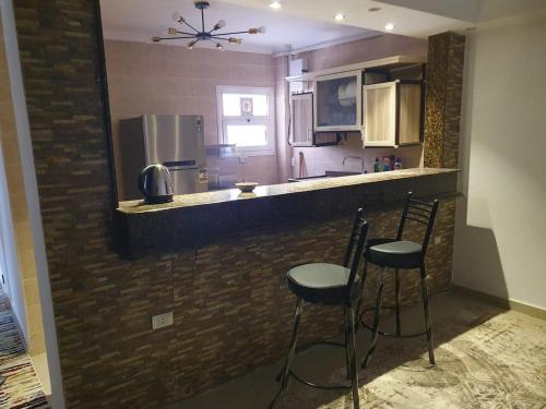 a kitchen with two stools at a bar with a counter top at Madinaty modern cozy apartment in Madinaty