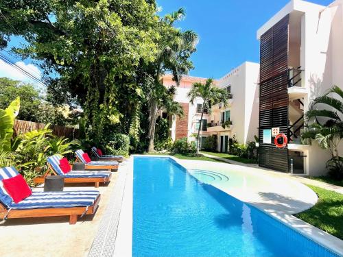 a swimming pool with lounge chairs next to a building at TENDA Comfortable Apartments in Playa del Carmen