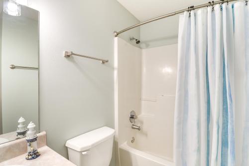 a white bathroom with a shower curtain and a toilet at Walk to Beach Condo with Balcony in Gulf Shores! in Gulf Shores